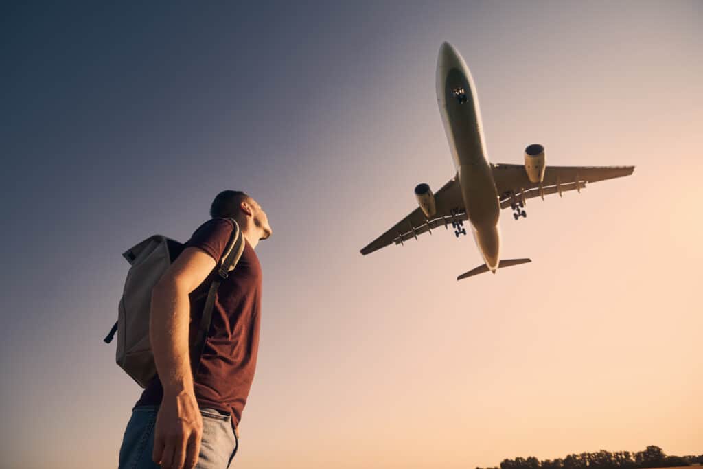 Viajante olhando para cima para o pouso do avião no aeroporto