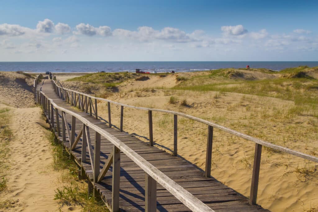 A ponte está localizada em frente a uma área gramada e é cercada por dunas de areia