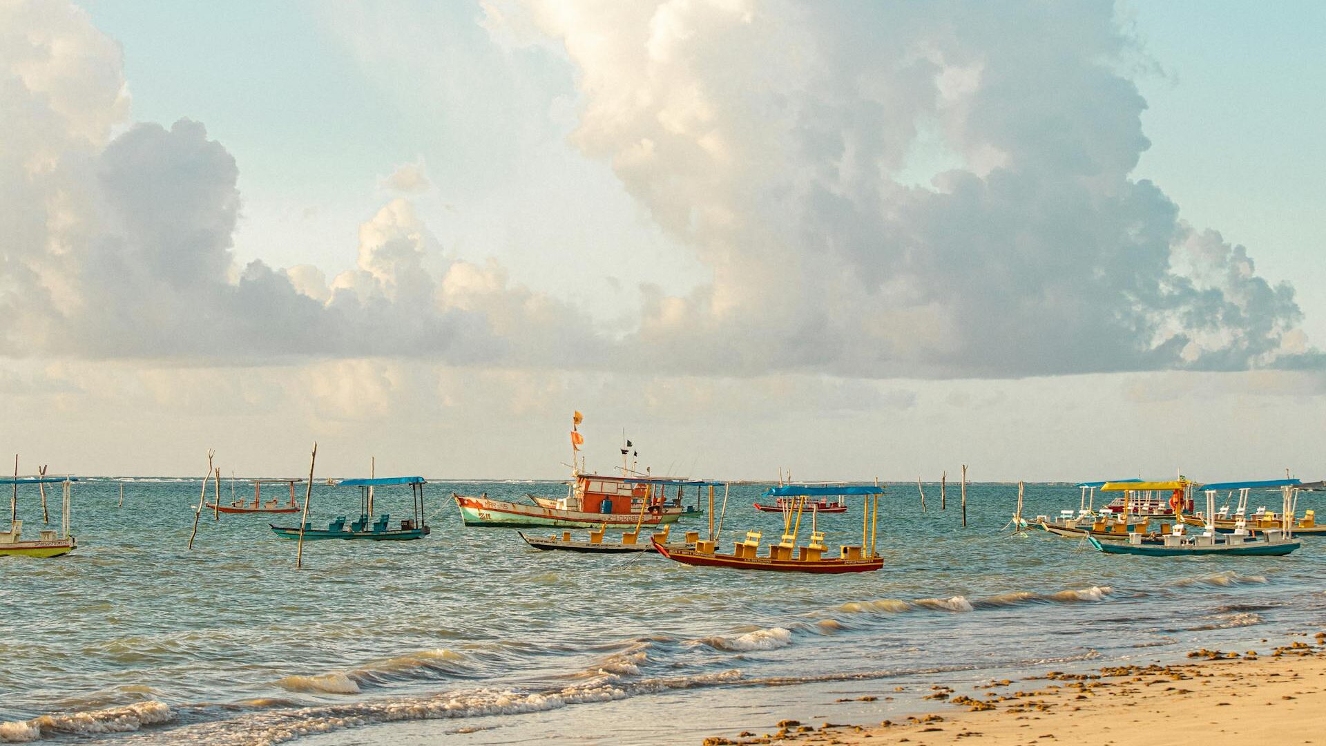 Praias do Nordeste brasileiro com barcos de pesca tradicionais, mar calmo e areia clara