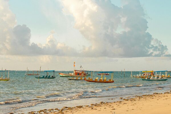 Praias do Nordeste brasileiro com barcos de pesca tradicionais, mar calmo e areia clara