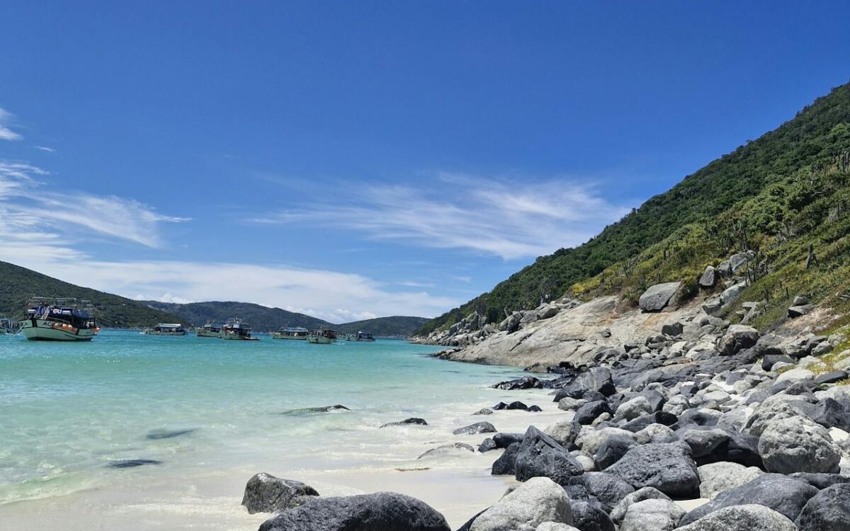 Praia paradisíaca em Arraial do Cabo com mar azul-turquesa, areia branca e formações rochosas no litoral do Rio de Janeiro