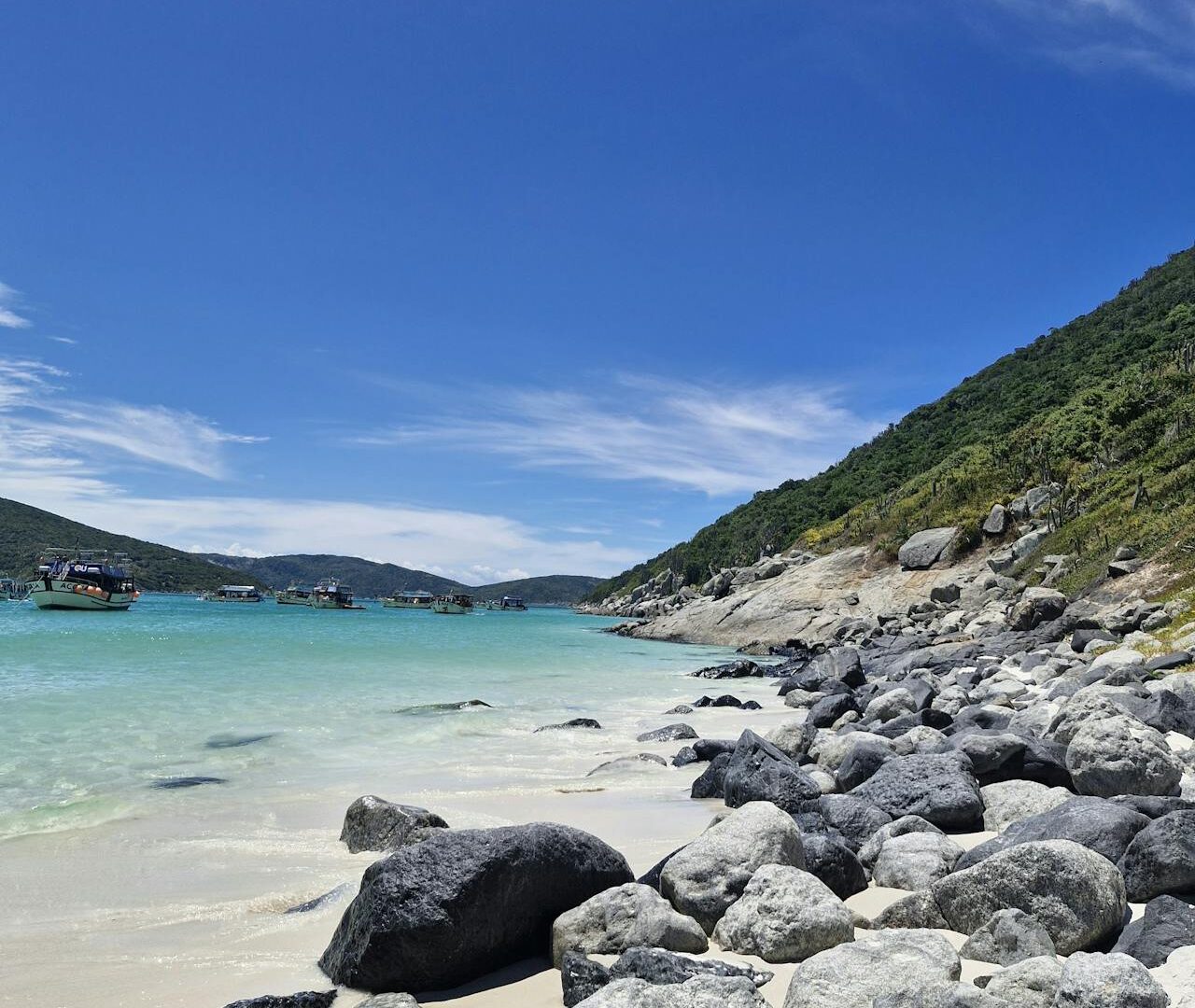 Praia paradisíaca em Arraial do Cabo com mar azul-turquesa, areia branca e formações rochosas no litoral do Rio de Janeiro