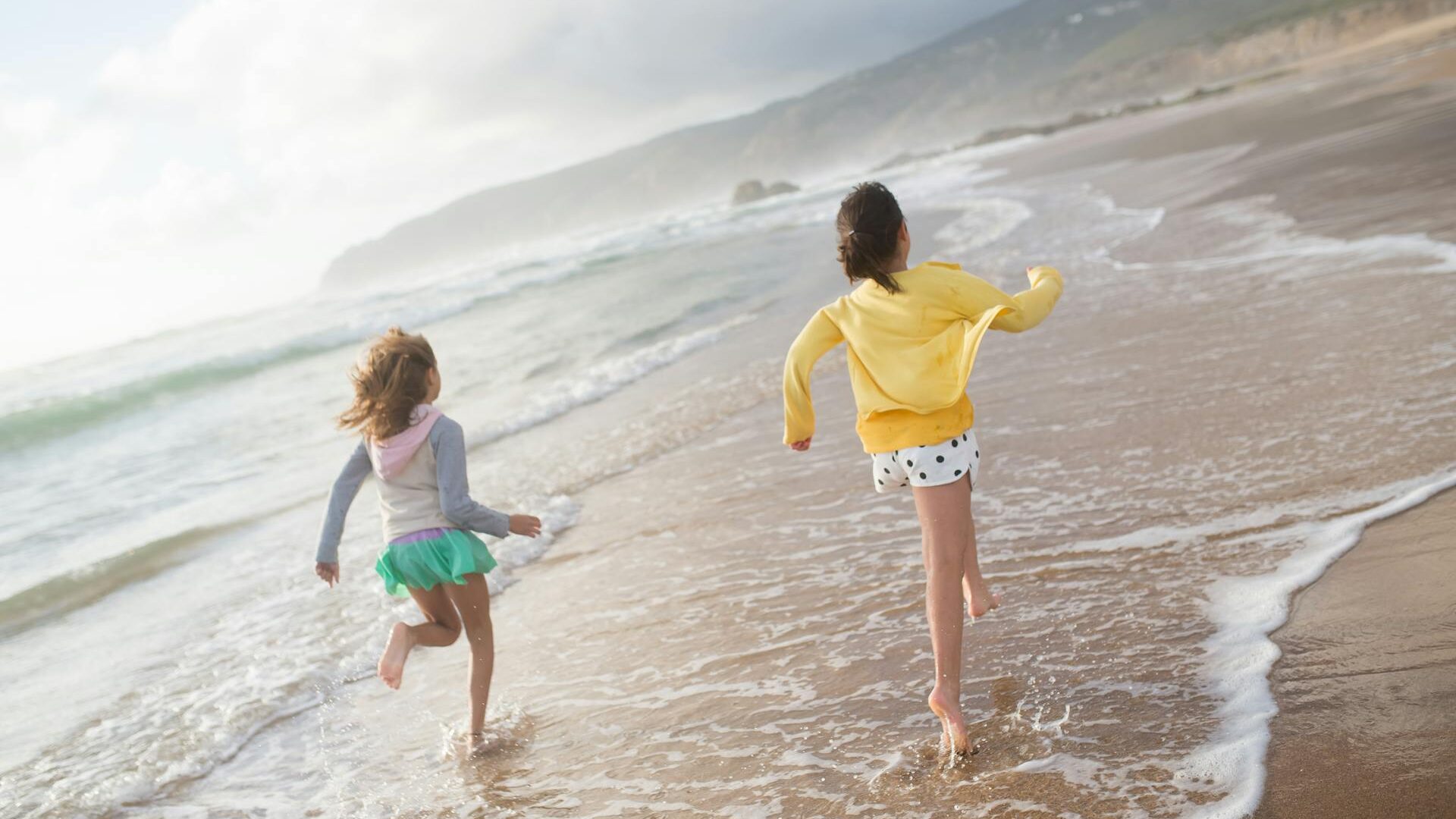 Crianças brincando na beira do mar em praia tranquila do Brasil, ideal para famílias com águas calmas e areia segura